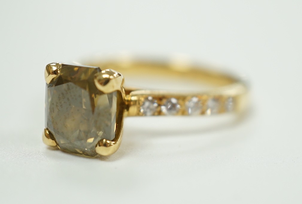 A modern 18ct gold and single stone cut cornered rectangular modified brilliant cut fancy dark brown-greenish yellow diamond, with diamond set shoulders and accompanying GIA report dated 20/12/2013, stating the stone to